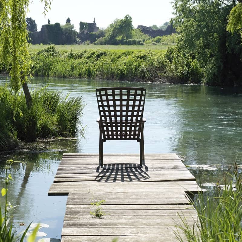Ein Sessel steht mitten im Gr&uuml;nen auf einem Holzsteg, der zu einem See f&uuml;hrt